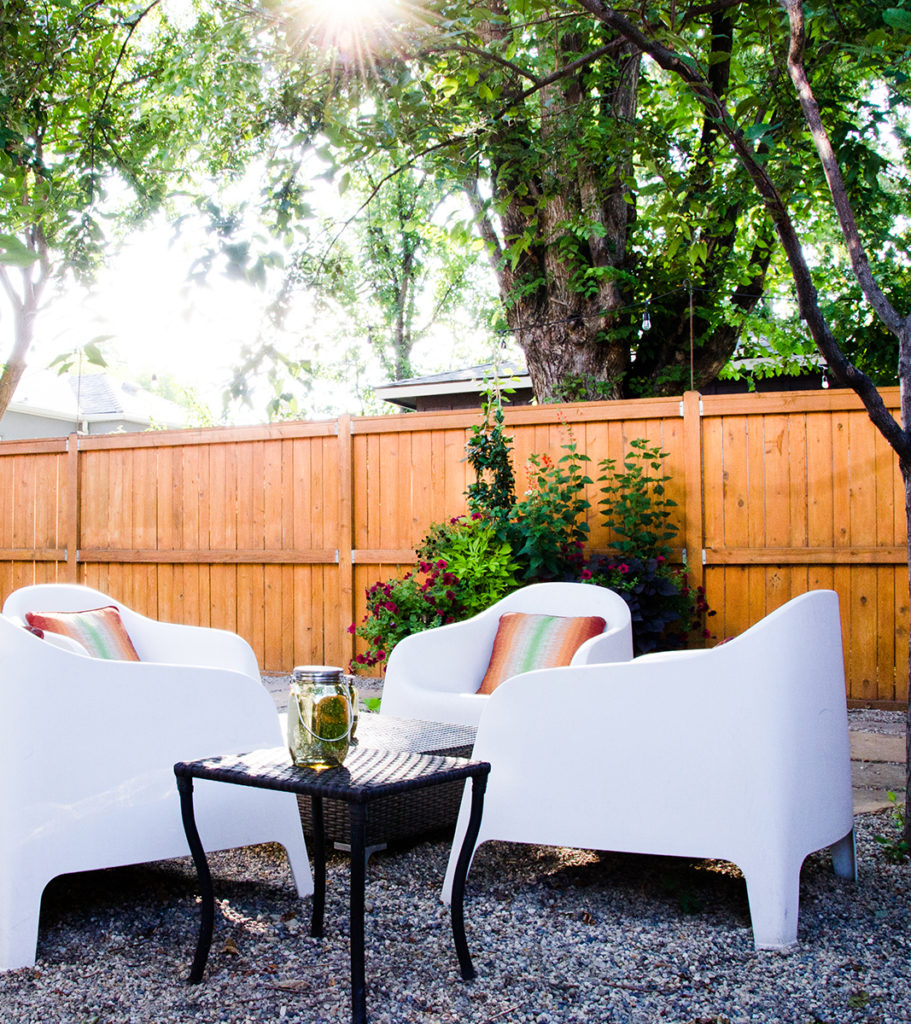 Backyard seating area of the Boise Guesthouse showing four white chairs and pillows